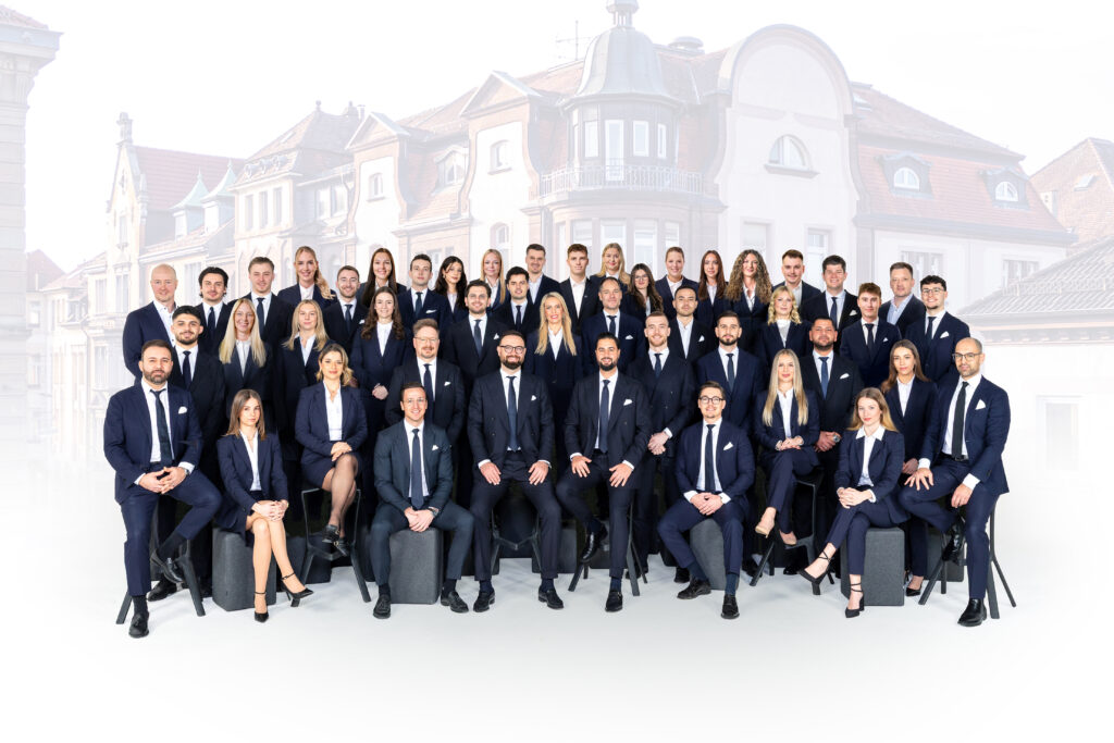 Das ganze Tam von Weitblick Immobilien. Damen und Herren in Anzügen, alle in dunkel blau.