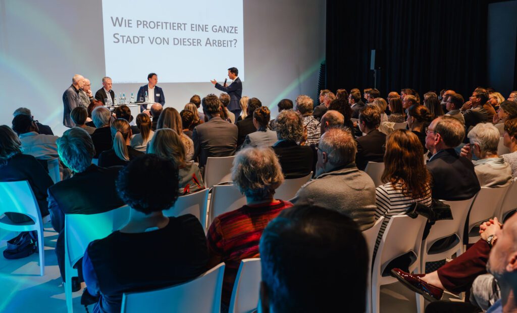 Elmar Kunz moderiert die Podiumsdiskussion vor einem vollen Saal