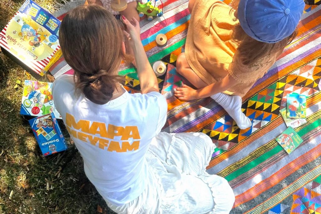 eine erwachsene Frau spielt mit einem Kind auf einer Spieldecke